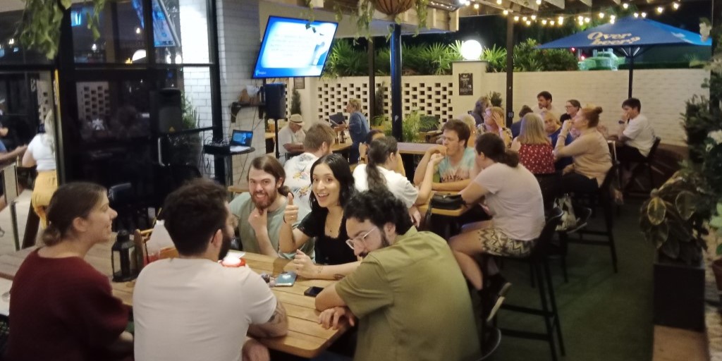 Photo several teams of Gen-Z adults enjoying a weekly pub trivia game